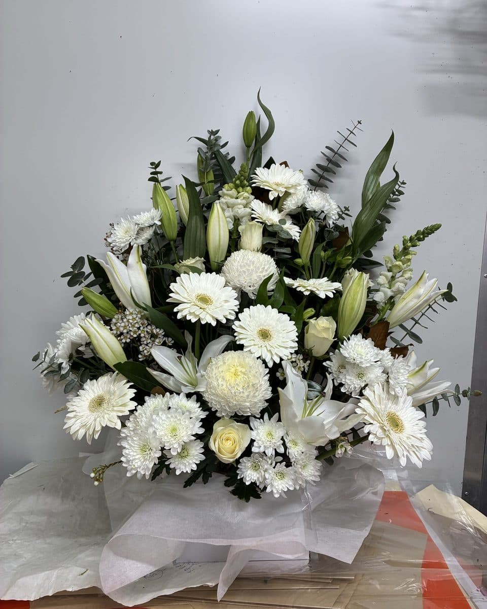 White sympathy arrangement of oriental lilies, gerberas, chrysanthemums and eucalyptus in a white box