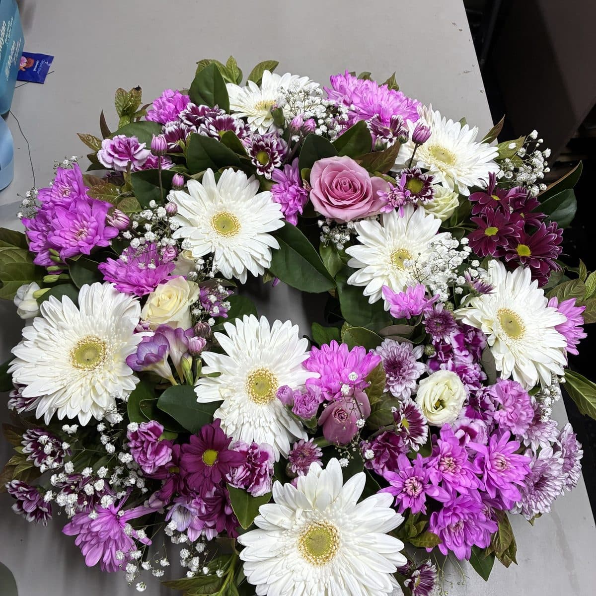 Round wreath of white gerberas, purple and white chrysanthemums, pink roses and baby's breath